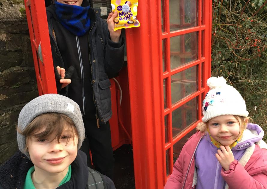 Bill, Raffie and Eliza Clatworthy-Edwards finding Roof-us easter prize outside a red telephone box..