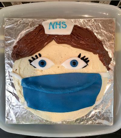 Cake decorated to look like a face with a Covid mask on