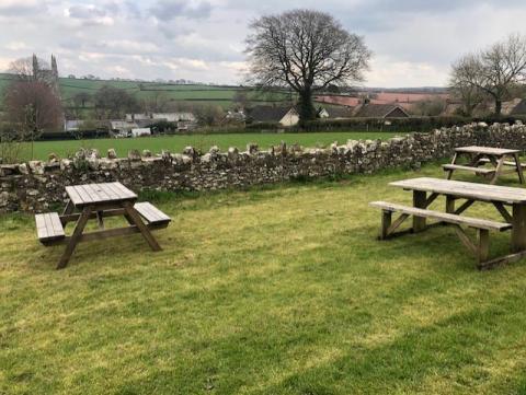 Photo of picnic benches in situ overlooking a view of surrounding area.