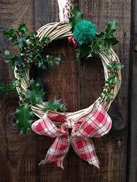 A wreath made from willow, decorated with holly and ribbon hanging on a door