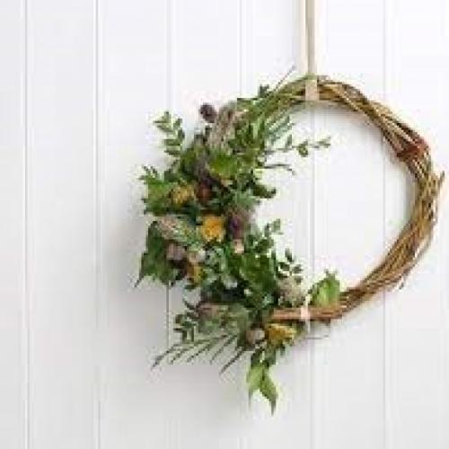 A decorated willow wreath with flowers on one side.