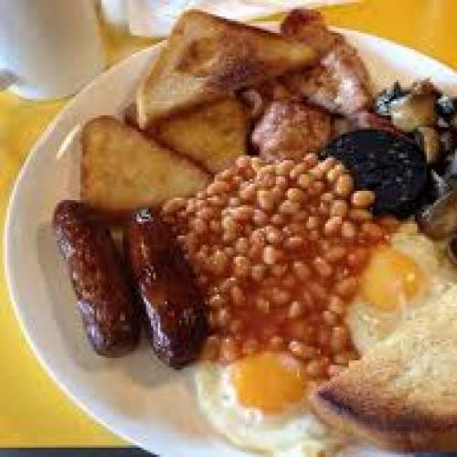 A full english breakfast on a plate with sausage, bacon, egg, mushrooms and beans